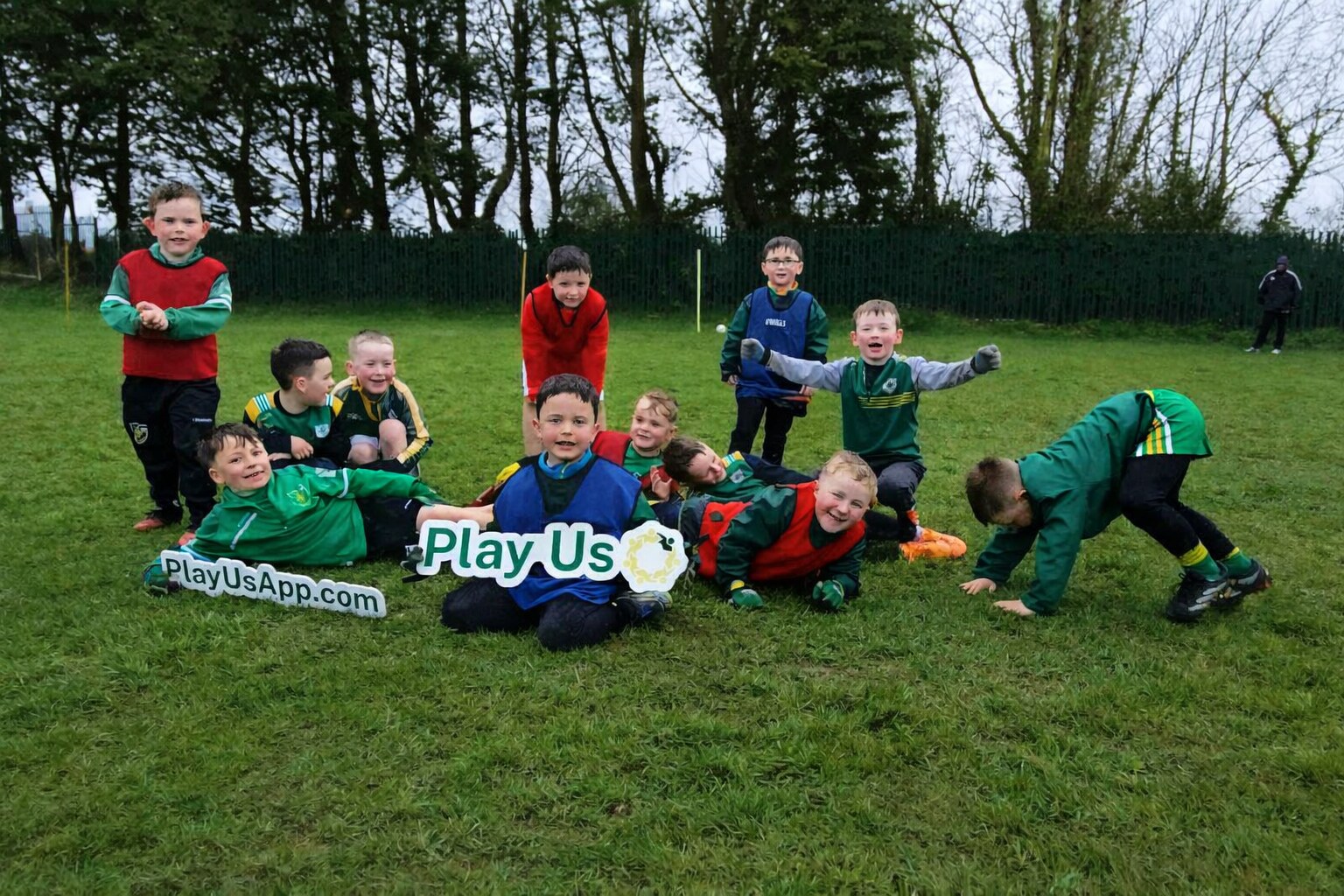 Young players in different coloured kits celebrating together with Play Us signs